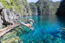 Quattro giovani si tuffano nelle acque del lago Kayangan a Palawan, Filippine. Questo bacino d'acqua è considerato uno dei più limpidi di tutta l'Asia nonchè uno ...