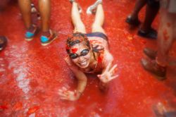 Una ragazza immersa nel succo dei pomodori che rimane a terra dopo la battaglia della Tomatina a Buñol (Comunità Valenciana, Spagna) - © Iakov Filimonov / Shutterstock.com ...