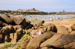 Ragazze prendono il sole sulle rocce di Ploumanac'h, Francia. Sullo sfondo, barche con la bassa marea 