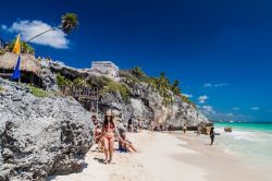 Relax in spiaggia sotto le rovine dell'antica città di Tulum, Messico. L'antico edificio in pietra chiamato Castillo è arroccato su una scogliera e domina dall'alto ...