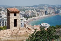 Resti antichi nella città di Calpe, Spagna, con la spiaggia affollata sullo sfondo - © Daniel Leppens / Shutterstock.com