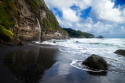 Sabbia nera su una spiaggia nell'isola di Dominica, Caraibi. Sullo sfondo, la cascata di Wavine Cyrique.

