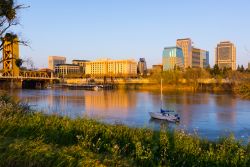 Sacramento al tramonto, California - Una bella immagine della città fotografata con i riflessi color arancio al calar del sole: le acque navigabili del fiume hanno sullo sfondo palazzi ...