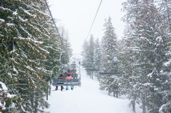 Sciatori sulla seggiovia durante una nevicata a Fernie, British Columbia, Canada. Gli appassionati di sci troveranno chilometri di piste, seggiovie e skilift per dedicarsi al loro sport preferito ...