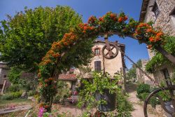 Scorcio bucolico nel cuore della medievale Perouges, Francia: un arco ricoperto da fiori. 

