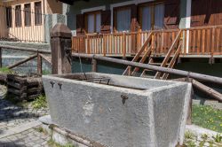 Scorcio del borgo di Claviere, provincia di Torino, Piemonte: una fontana in legno con vasca in pietra.
