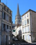 Scorcio di una strada nella città francese di Niort, Nuova Aquitania. Sullo sfondo la chiesa di Notre Dame: i pinnacoli smerlati sembrano alleggerire la torre quadrata sormontata dall'alta ...