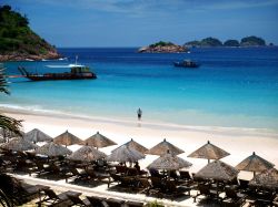 Sdraio e ombrelloni di paglia su una spiaggia a Redang, Malesia. L'isola offre diverse strutture ricettive fra cui scegliere per trascorrere una vacanza all'insegna del relax e delle ...
