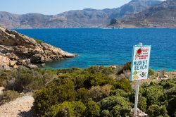 Un segnale fatto a mano per la spiaggia nudista dell'isola di Telendos, Grecia, di fronte al villaggio di Myrties - © DbDo / Shutterstock.com