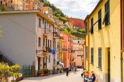 Scorcio fotografico all'interno del borgo di Manarola, Cinque Terre, Liguria. Un momento di relax per turisti e abitanti durante una bella giornata di sole.
