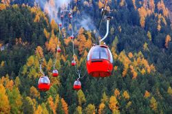 Skilift per l'Alpe di Siusi dal centro sciistico di Ortisei, Trentino Alto Adige. Sullo sfondo, montagne con foliage autunnale. 
