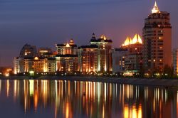 Skyline notturno di Astana, Kazakistan - Una bella immagine della capitale kazaka fotografata di notte quando le luci dei suoi edifici si riflettono nelle acque del fiume Ishim su cui sorge ...