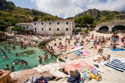 Spiaggia affollata alla vecchia Tonnara di Scopello, provincia di Trapani (Sicilia). Un tempo tenuta medievale destinata alla pesca del tonno, questa struttura è oggi un museo oltre che ...