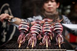 Spiedini di calamari in un mercato di strada a Osaka, Giappone.

