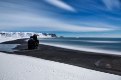 Una splendida immagine dei faraglioni di Reynisdrangar sulla spiaggia di Reynisfjara, Islanda. La luce della luna e l'aurora, complice anche la neve, rendono il paesaggio di questo tratto ...