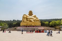 Turisti di fronte alla grande statua d'oro del Buddha a Qianfo Shan, Jinan, Cina. Questa piccola collina a sud di Jinan ospita templi, grotte, padiglioni, terrazze, torri e l'imponente ...