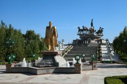 Statua di Niyazov e, sullo sfondo, scultura ai cavalli in un parco di Ashgabat, Turkmenistan. Noto anche come il "Grande Condottiero del Turkmenistan", Niyazov è stato presidente ...