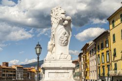 La statua di un leone e le case colorate lungo il fiume Arno, Toscana.



