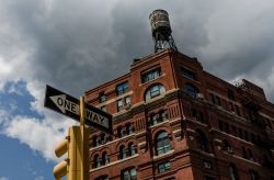 Un edificio storico in mattoni di New York City sormontato da un serbatoio dell'acqua (water tower)