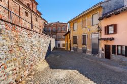Strada di ciottoli fra le mura della città e le abitazioni dalle facciate colorate e in mattoni a La Morra, Cuneo, Piemonte
