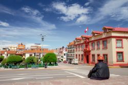 Street view a Puno, Perù: un lavoratore con elmetto seduto di fronte alla Plaza de Armas in un caldo pomeriggio estivo - © Simon Mayer / Shutterstock.com