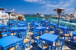 Taverna nel villaggio di Naoussa, Paros. Ricorda, se mai ce ne fosse bisogno, il colore del cielo e del mare: tavoli e sedie, dalle tonalità azzurre, si affacciano sulle acque del Mar ...