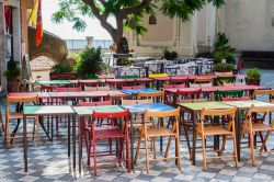 Tavoli colorati in un ristorante pizzeria della piazza principale di Castelmola, Sicilia. A' Mola, questo il nome in siciliano della cittadina di poco più di mille abitanti, fa parte ...