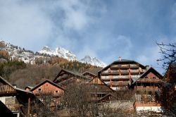 Tipiche case residenziali nello ski resort di Vaujany, Francia. Sullo sfondo, le vette innevate dei monti.
