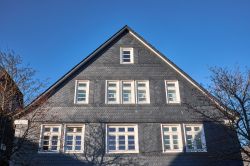 Il tradizionale tetto in ardesia di una casa a Winterberg, Germania. La caratteristica facciata è impreziosita da finestre in legno bianco.

