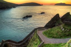 Tramonto sul percorso verso Dunquin Pier a Dingle, Irlanda. Questa località si trova all'estremità settentrionale di una piccola e graziosa baia circondata da scogliere rocciose ...