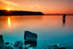 Tramonto sul lago di Bracciano a Anguillara Sabazia, provincia di Roma, Lazio. Riflessi arancioni sulle acque azzurre del bacino lacustre rendono ancora più suggestiva l'atmosfera ...