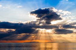 Un suggestivo tramonto con i raggi del sole che si insinuano tra le nuvole sul Mar Tirreno presso la città di Follonica, in provincia di Grosseto - foto © Shutterstock