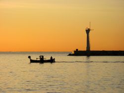 Tramonto sul porto di La Ciotat, Francia, con una barca in mare e il faro.
