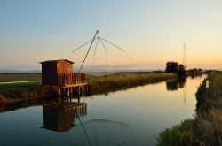 I padelloni, le capanne per la pesca, fotografate al tramonto in una canale che alimenta le saline di Cervia, in Emilia-Romagna - © lafoto / Shutterstock.com
