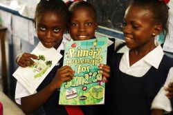 Tre giovani studentesse africane con il libro di matematica per la Giamaica, Kingston - © Danita Delmont / Shutterstock.com