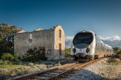 Treno in transito davanti a un antico edificio in pietra nei pressi della stazione di Lumio, Corsica - © Jon Ingall / Shutterstock.com