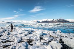 Una turista sulle rive della Jokulsarlon Glacier Lagoon, il lago sul quale galleggiano gli iceberg che si staccano dal ghiacciaio Breiðamerkurjökull, in Islanda.
