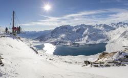 Turisti ammirano il lago del Moncenisio e le montagne innevate dal belvedere panoramico al Col de la Met, Francia (Val Cenis) - © antb / Shutterstock.com