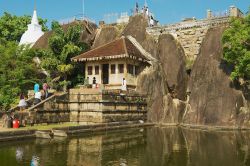 Turisti nel tempio di roccia di Isurumuniya nei pressi di Anuradhapura, Sri Lanka. Questo suggestivo tempio di roccia è incastonato attorno a un laghetto di loto: salendo in cima alla ...