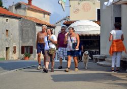 Turisti passeggiano in una strada di Premantura (Istria) mangiano il gelato - © teal sun / Shutterstock.com