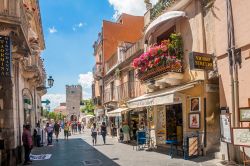 Turisti passeggiano nei pressi di una porta d'accesso alla cittadella di Taormina, Sicilia. Il centro storico cittadino si snoda lungo corso Umberto e appare come chiuso da porte laterali ...