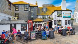 Turisti seduti nel dehors dello Sloop Inn a St. Ives, Cornovaglia, Regno Unito. Questa locanda situata sul molo è una delle più antiche della Cornovaglia. Costruito con macerie ...