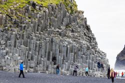 Turisti vicino al monte Reynisfjall sulla spiaggia lavica di Reynisfjara, Vik i Myrdal, Islanda. Questa montagna si eleva per 340 metri e per 5 chilometri in lunghezza. Di particolare interesse ...