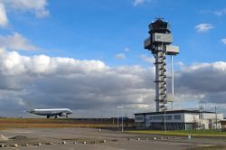 Un aereo sulla pista di atterraggio dell'aeroporto di Lipsia, Germania, con la torre di controllo in una giornata nuvolosa.

