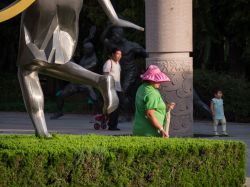 Un cinese al lavoro con indosso il tradizionale copricapo, qui colorato, all'Olympic Sculptural Culture Park di Qingdao, Cina - © Greenybot / Shutterstock.com