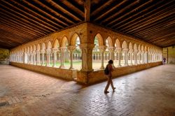 Un fedele nel chiostro dell'abbazia di Moissac (Francia) dedicata a San Pietro. Patrimonio dell'Umanità dell'Unesco, è un capolavoro dell'arte romanica - © ...