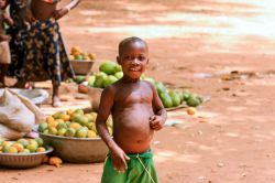 Un giovane ragazzino sorride in un mercato di frutta a Ouagadougou, Burkina Faso - © Dave Primov / Shutterstock.com