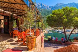 Un grazioso ristorante nel borgo di Porto, Corsica, in estate. Sullo sfondo, uno scorcio della baia di Porto fra scogliere a strapiombo e paesaggi mozzafiato - © Pawel Kazmierczak / Shutterstock.com ...