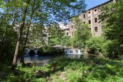 Un grazioso scorcio di Olot con vecchi edifici immersi nella vegetazione del lungofiume, Catalogna, Spagna.



