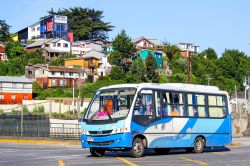 Un minibus percorre la città di Puerto Montt, Cile. Sullo sfondo, le tipiche case colorate in legno - © Art Konovalov / Shutterstock.com